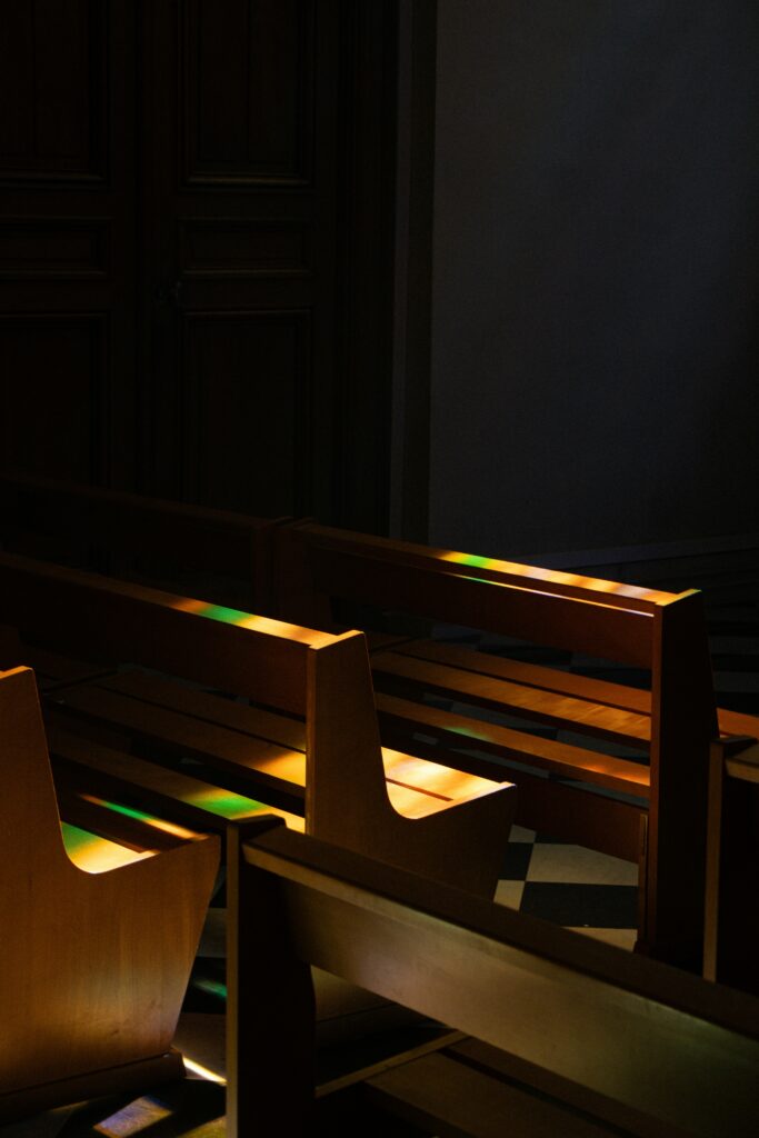 Church Hurt Is Real: 7 Powerful Truths That Can Heal What Religion Broke 2 Empty wooden pews with stained glass reflections symbolizing church hurt